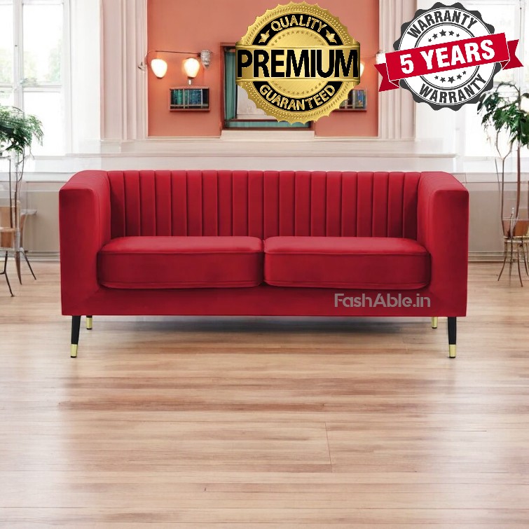 A red velvet sofa with vertical stitching is centered in a room with hardwood floors, featuring gold-tipped legs. Decorative wall lights accent the space. Overlaid text invites you to explore the Premium Quality Guaranteed badge and a 5 Years Warranty emblem.