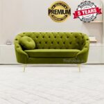 A stylish green tufted sofa with a round cushion graces a room featuring a light-colored floor, inviting you to explore its comfort. Above it, badges proudly display Premium Quality Guaranteed and 5 Years Warranty, echoing the craftsmanship you can shop for now.