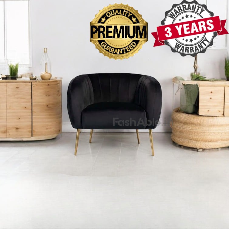 A black armchair with gold legs takes center stage in an elegantly styled room. Flanked by two round wooden tables adorned with green plants, it invites you to explore comfort and class. A Premium Guaranteed and 3 Years Warranty badge promise the best buy for discerning individuals.