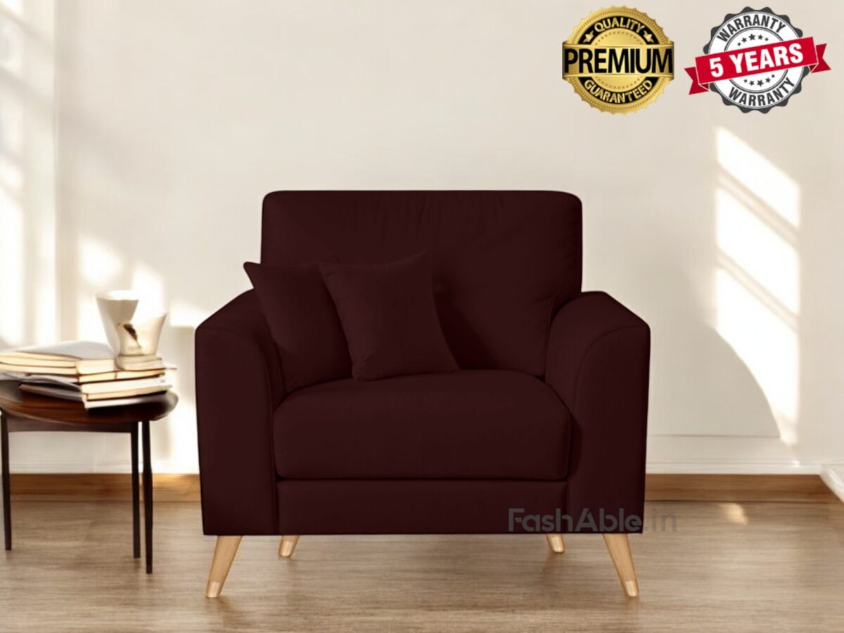 A deep brown armchair with wooden legs graces the bright room, inviting you to explore its comfort. It comes with matching cushions, a small table stacked with books, and a mug. The Premium Quality and 5 Years Warranty badges assure you its a stylish purchase from Fashable.