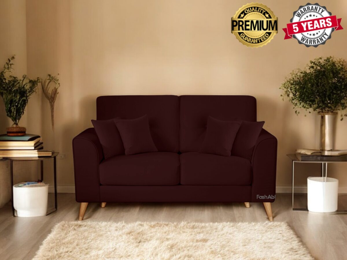 A cozy living room with a dark brown sofa adorned with two cushions invites you to explore its charm. The room features two potted plants, stacked books on a small table, and a beige rug. Banners proudly showcase Premium Quality and a 5 Years Warranty, enticing you to buy.